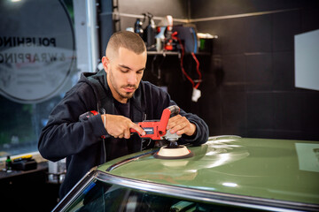Young man using professional buffer tool to polish car