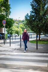 A visually impaired woman walking across a pedestrian crossing