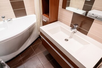 modern bathroom featuring a white tub, vanity with a sink, brown tiled floor, and beige and brown...
