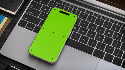 Phone with green screen mockup on laptop keyboard..