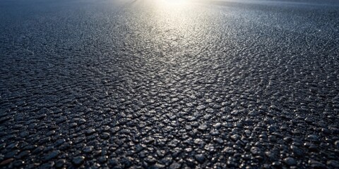 A Detailed Close-Up View of a Dark Asphalt Surface with Light Reflecting off its Textured Surface