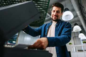 Man efficiently using a printer in a modern office environment during daytime hours