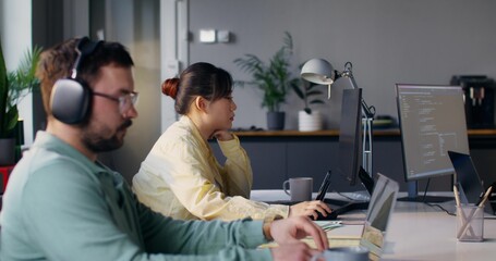 Obraz premium Young people of different nationalities work together in an office. They use computers.
