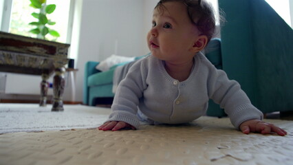 Baby on the floor, pushing up with arms, looking ahead with curiosity, actively exploring...