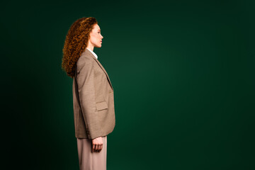 Side profile of a professional businesswoman in a formal suit on an elegant emerald green background