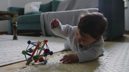 Baby reaching for colorful toy on mat, engaging in tactile play and sensory exploration, developing...