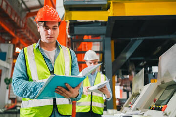Engineers in high-visibility vests inspecting industrial control systems in modern factory,...