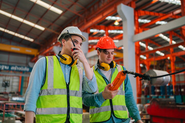 Engineer worker team of technicians collaborating on production line inside factory, wearing safety...
