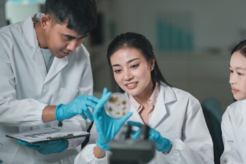 Young researchers collaborating in a modern laboratory, conducting chemical and biological experiments using microscopes, laptops, and test tubes to drive innovation and advance scientific education