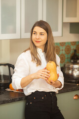 Smiling Woman in White Shirt Showing Split Pumpkin in Cozy Home Kitchen