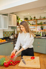 Light-Skinned European Woman Placing Sliced Red Bell Pepper into Clear Glass Bowl in Bright Kitchen