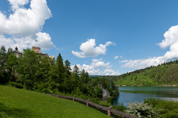 Fototapeta premium Niedzica Castle above Lake Czorsztyn in southern Poland, surrounded by forest and hills, under blue sky with clouds, summer landscape.