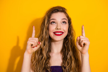 Cheerful young woman with red lipstick making positive gestures against a vibrant yellow background