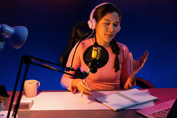 Smiling creative young beautiful Asian influencer talking in channel with positive podcast speech...