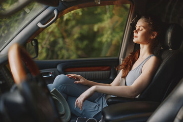 Young woman relaxing in car with eyes closed, enjoying calm moment in nature, wearing casual attire...