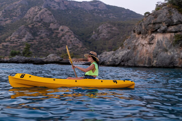 Young lady paddling the kayak from limestone cave towards