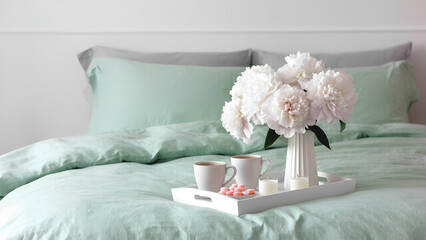 Huge white peonies bouquet and white wooden tray with hot black tea,