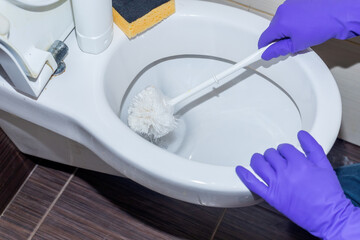 Man hand cleaning toilet with brush