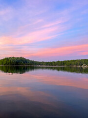 Fototapeta premium The sun sets pink and blue cotton candy skies over a quaint little lake in Northern Michigan on a hot summer night.