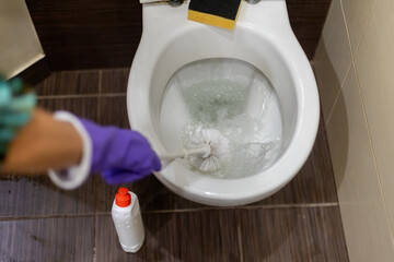 Man hand cleaning toilet with brush