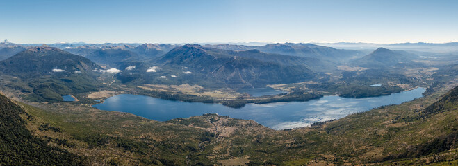 Lake Ñorquinco nestled amidst rolling, forested hills with distant mountain ranges of Los Andes, Patagonia, Argentina