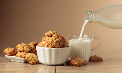 Oatmeal cookies and milk sit on a kitchen table.