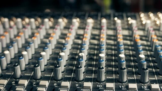 Pro audio mixing board faders and knobs.  Slider shot backing away from multi-track music recording equipment.
