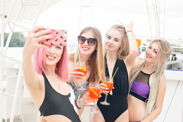 four attractive girls resting on the beach bar, drink a refreshing cocktail