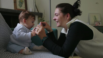 Mother holding object to engage baby, encouraging sensory exploration and focus, nurturing playtime interaction in a supportive home environment, early childhood learning