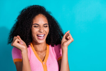 Excited young woman in pink outfit celebrating on turquoise background with vibrant expression