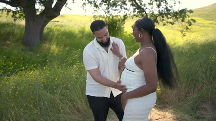 In a stunning outdoor setting, a joyful African American couple celebrates their pregnancy, fully embracing the delightful summer vibes while radiating love and connection in the beauty of nature