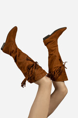 female legs raised up wearing cowboy boots on white background