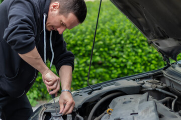 The car broke down while traveling..Mechanic's hand working under open hood of car. A frustrated...
