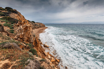 Scenic view of ocean waves crashing on rocky coast under cloudy sky, creating dramatic seascape
