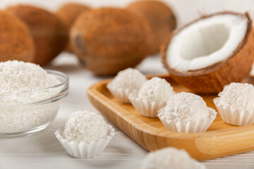Coconut candies on a wooden background. Candies with chocolate, almonds and delicate butter cream. Coconut flakes. tasty sweets.Tasty ball-shaped chocolate candies.Dessert. Space for text.copy space