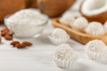 Coconut candies on a wooden background. Candies with chocolate, almonds and delicate butter cream. Coconut flakes. tasty sweets.Tasty ball-shaped chocolate candies.Dessert. Space for text.copy space