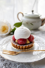 A Tart with strawberries and cream on a white plate