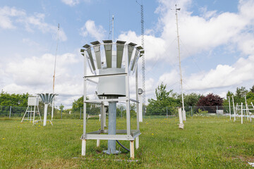 Meteorological station with rain gauge collectors and weather sensors installed on a grassy field
