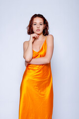 Portrait of attractive girl in orange dress in the studio