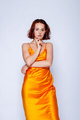 Portrait of attractive girl in orange dress in the studio