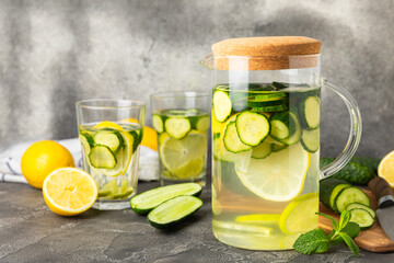 Cucumber water with lemon, lime and mint on a wooden table. Water infused with sliced...