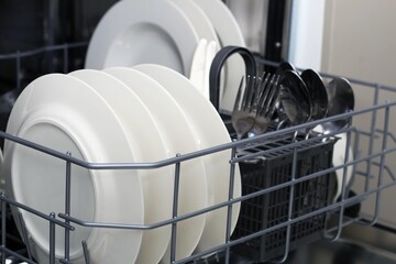 Clean dishes and utensils neatly arranged in a dishwasher after a meal, showcasing efficient kitchen organization
