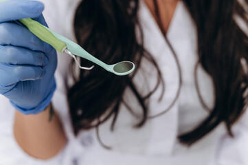 Hands of a medical professional holding a dental instrument in a modern clinic. Focus on precision...