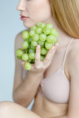 Woman holds grapes in the chest and hugs it with both hands.