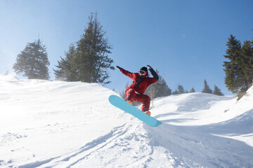 Active snowboarder jumping in mountains on a sunny day