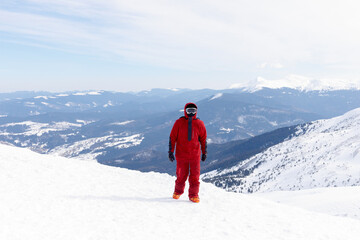 Snowboarder stands on backcountry slope and holds snowboard.