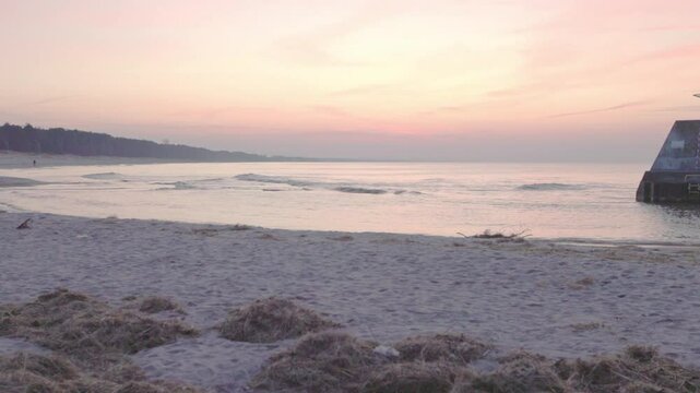 Sunset over calm Baltic waters near storm gates and breakwater in Łazy. 