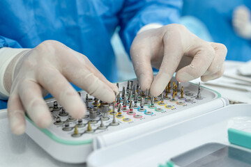Male dentist choosing dental tools during appointment or polish brush while preparing for work at...