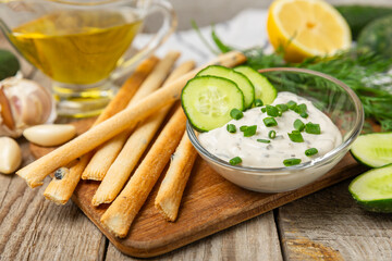 Cucumber sour cream tzatziki sauce on a wooden table.Tartar sauce. Traditional delicious appetizer. yogurt sauce. Tzatziki with ingredients cucumber, garlic,dill,lemon,mint. salad dressing.Copy space