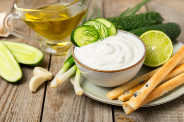 Cucumber sour cream tzatziki sauce on a wooden table.Tartar sauce. Traditional delicious appetizer. yogurt sauce. Tzatziki with ingredients cucumber, garlic,dill,lemon,mint. salad dressing.Copy space